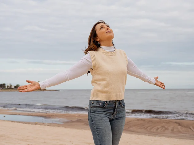 Mujer sintiéndose plena junto al mar